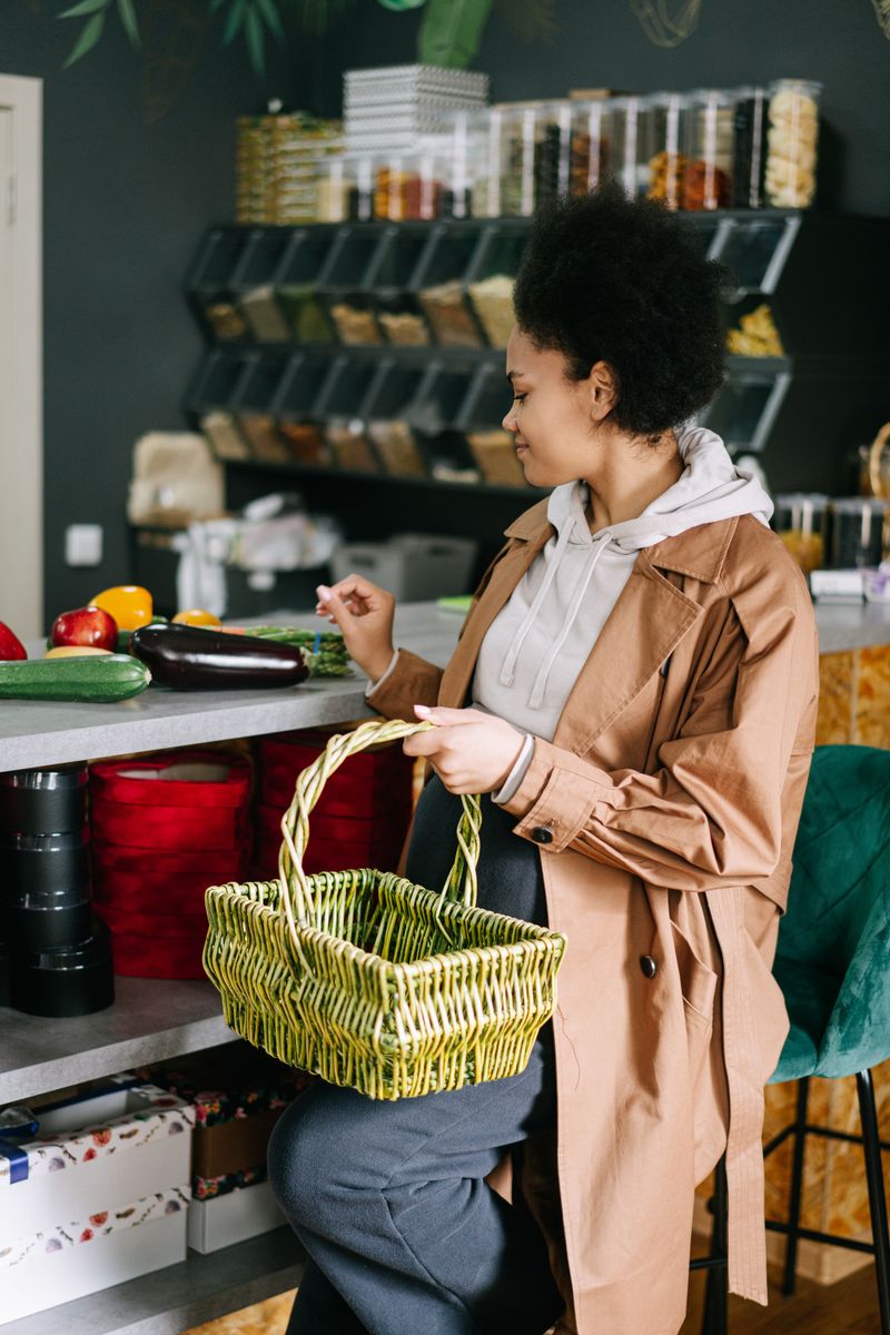 A parent and child reviewing a handwritten grocery list together at a kitchen table with reusable shopping bags nearby.